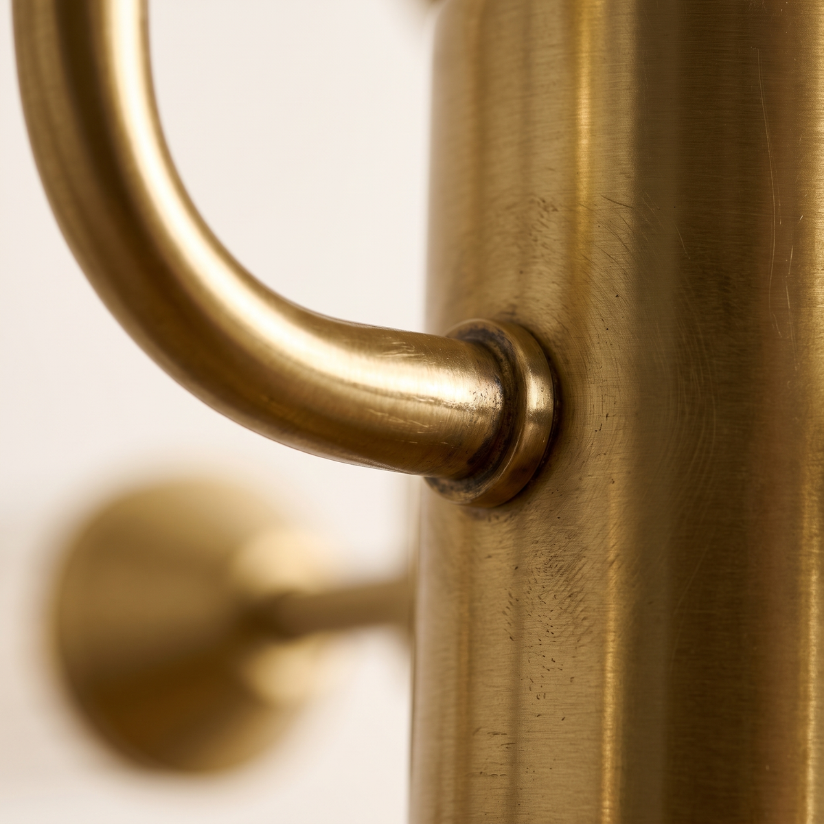 Close detail of a satin brass arm joining the central column of the Regmont chandelier