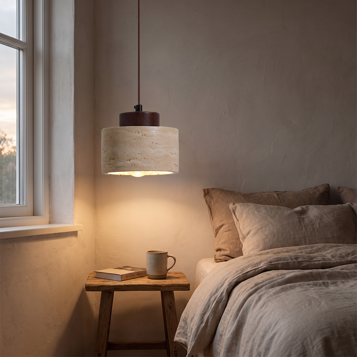 Tivoli travertine pendant light lit beside a bed in the evening