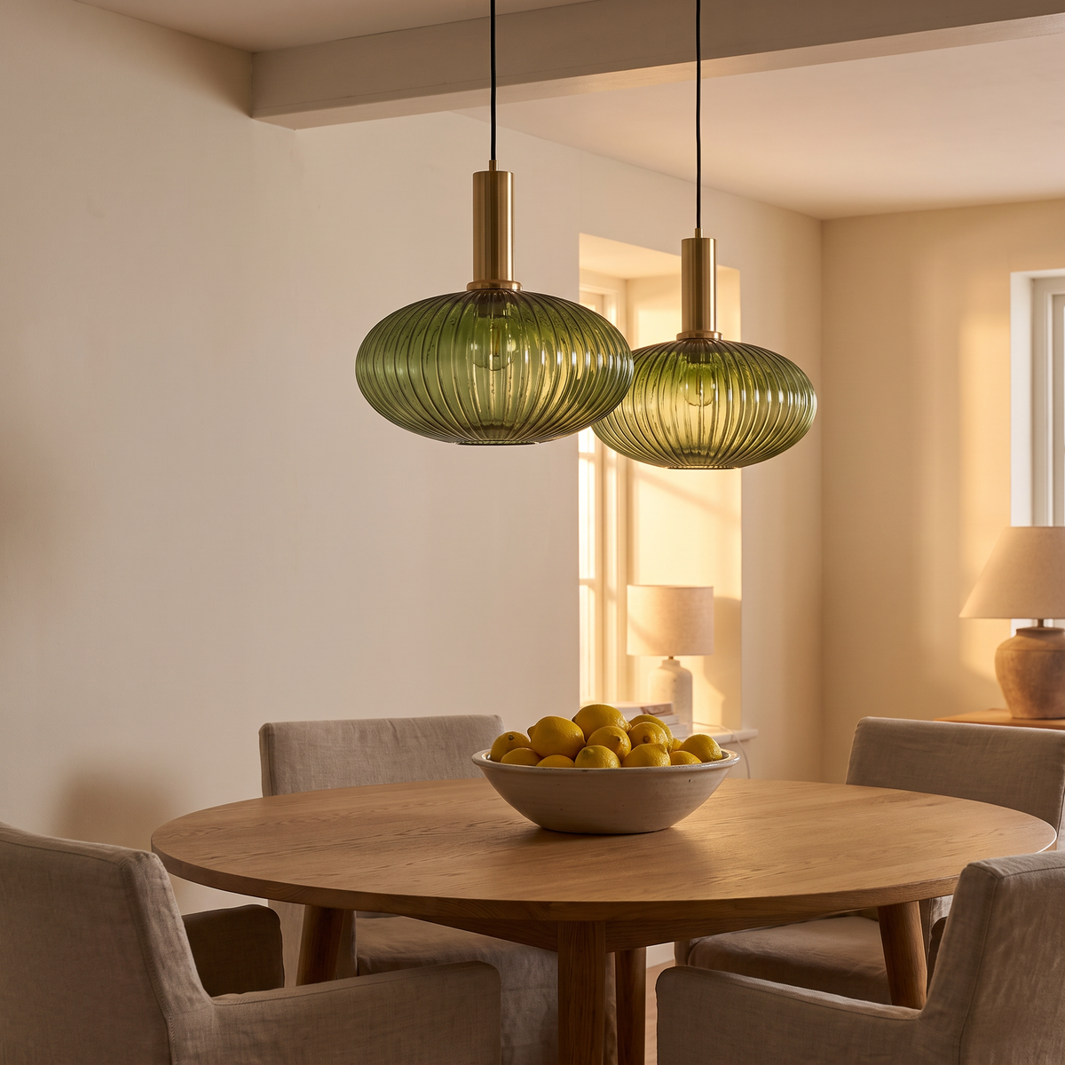 Two Fenwick green ribbed glass pendants over a round oak dining table