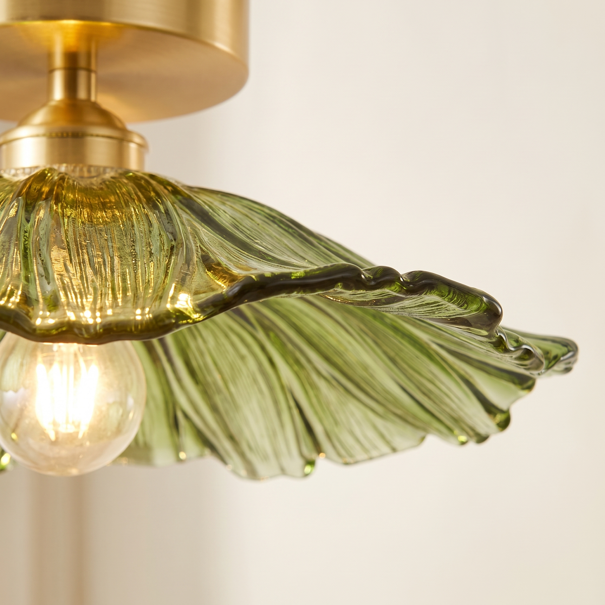 Close up of the ruffled green glass edge and brass holder