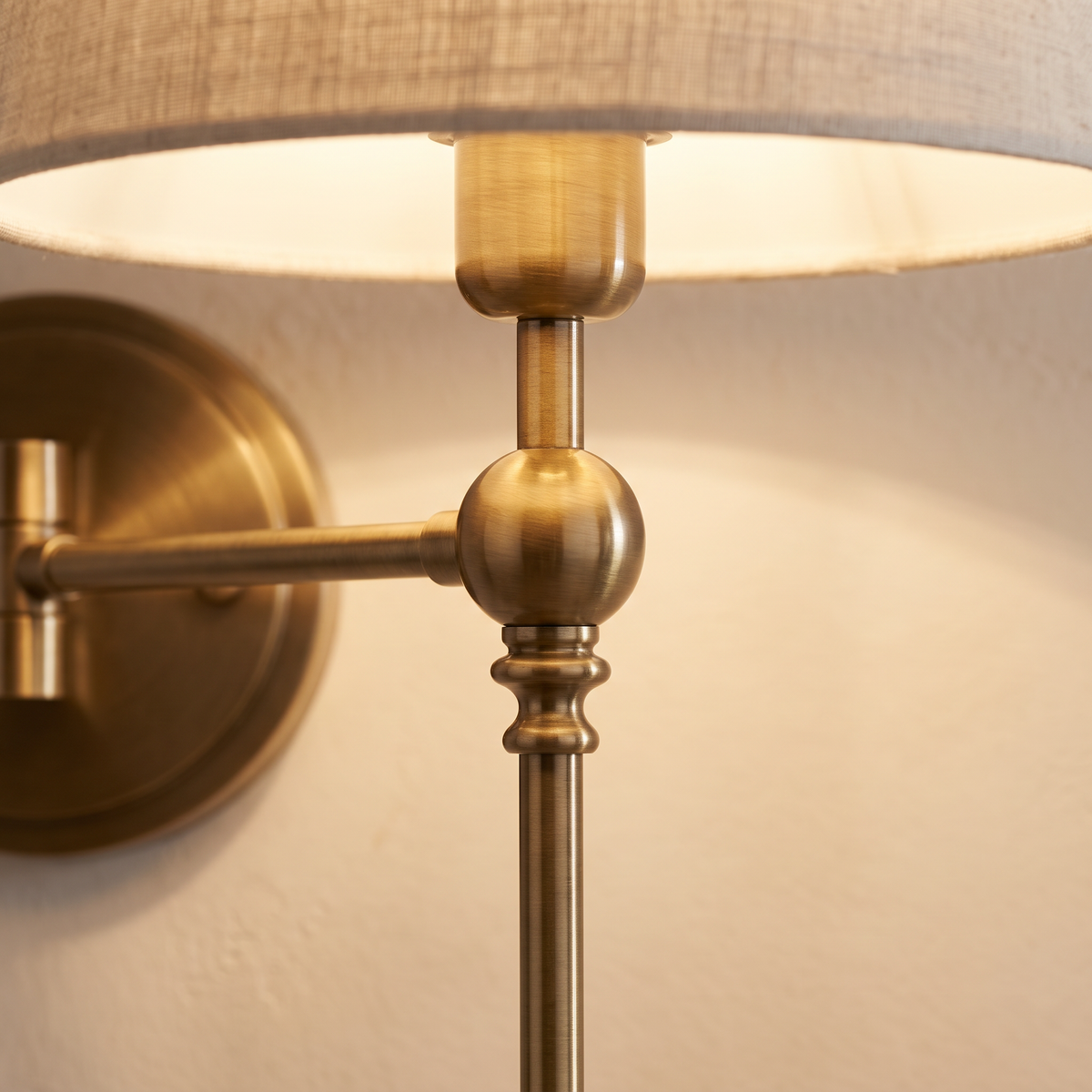Close up of the brushed brass arm and linen shade
