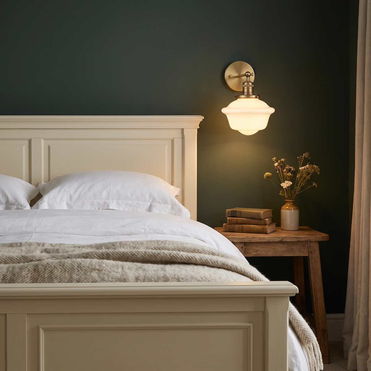 Ely milk glass wall light lit above a bedside table against a dark green wall