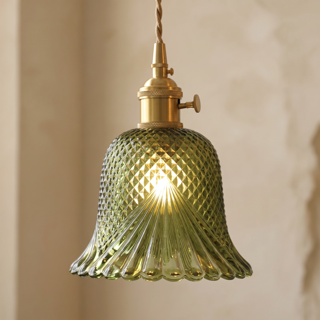Close up of the green Lavenham cut glass shade and brass lamp holder with its turn knob, lit