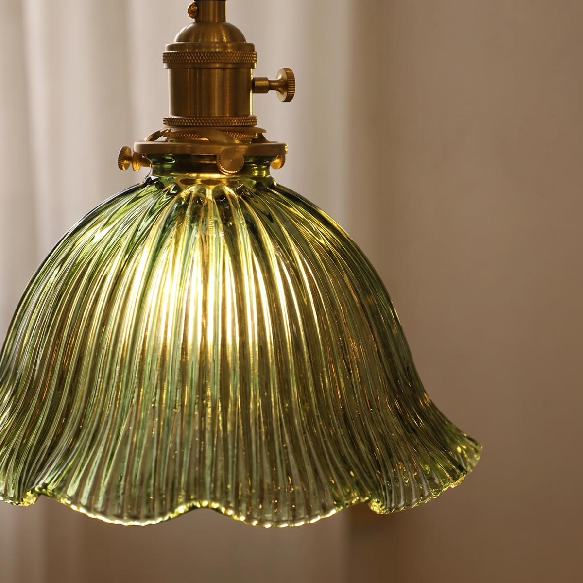 Close up of the Dedham green fluted glass, scalloped rim and brass lamp holder, lit