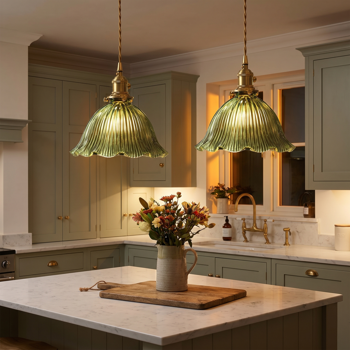Two green Dedham pendant lights lit above a marble kitchen island