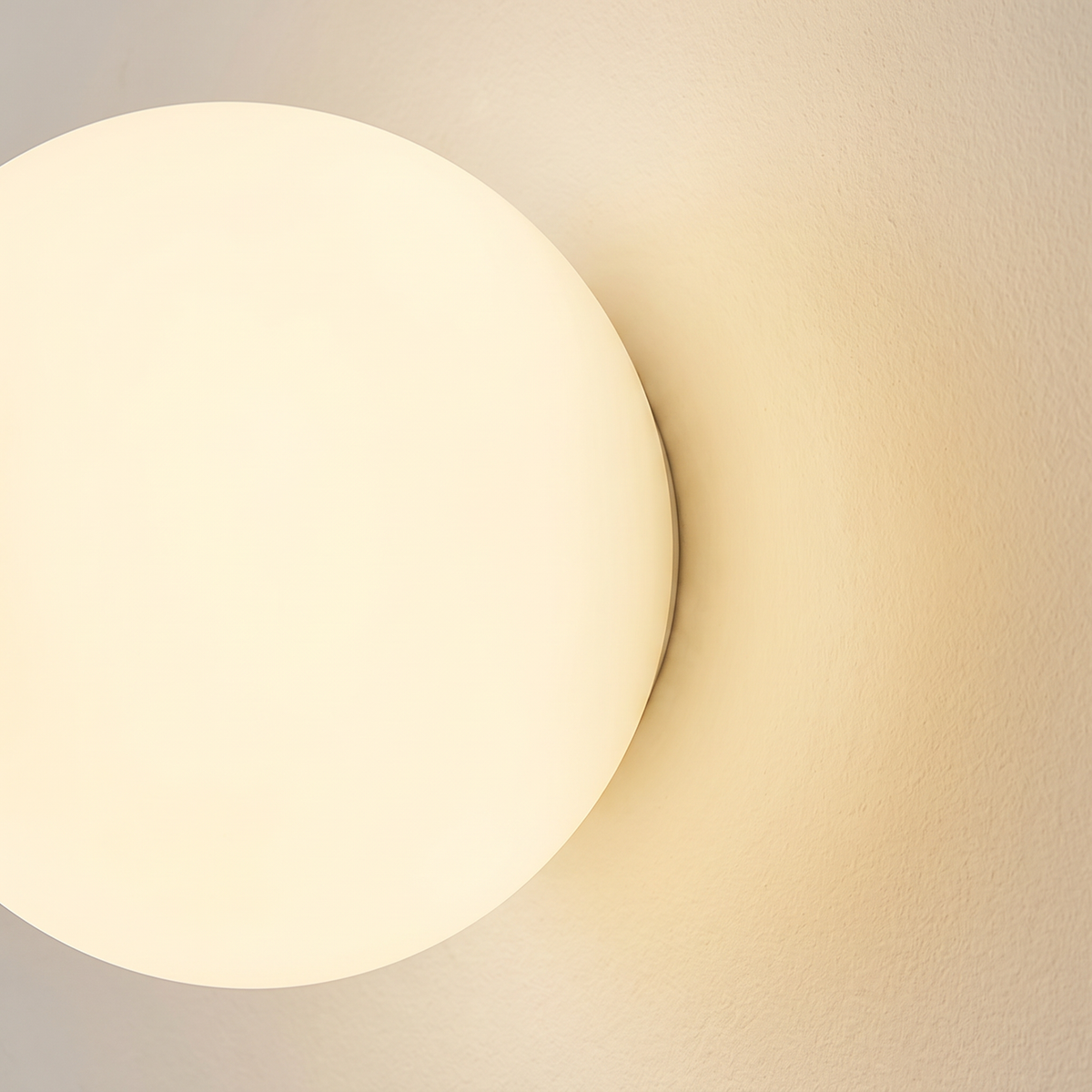 Close up of the Aldeburgh frosted opal glass globe glowing against the wall