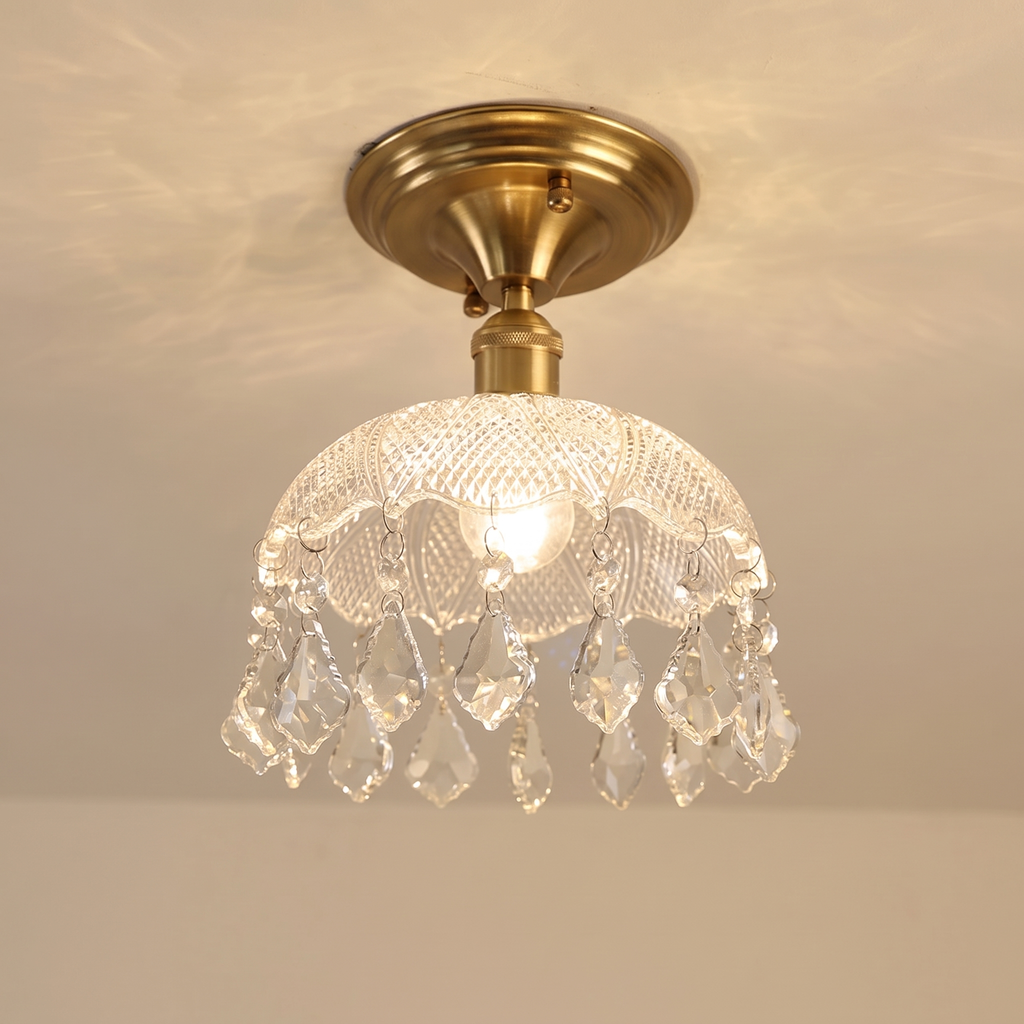 Kersey crystal drop flush ceiling light with a clear cut glass dome and brass base, lit