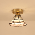 Orford stained glass flush ceiling light with clear, cream and blush leaded glass on a brass base, lit