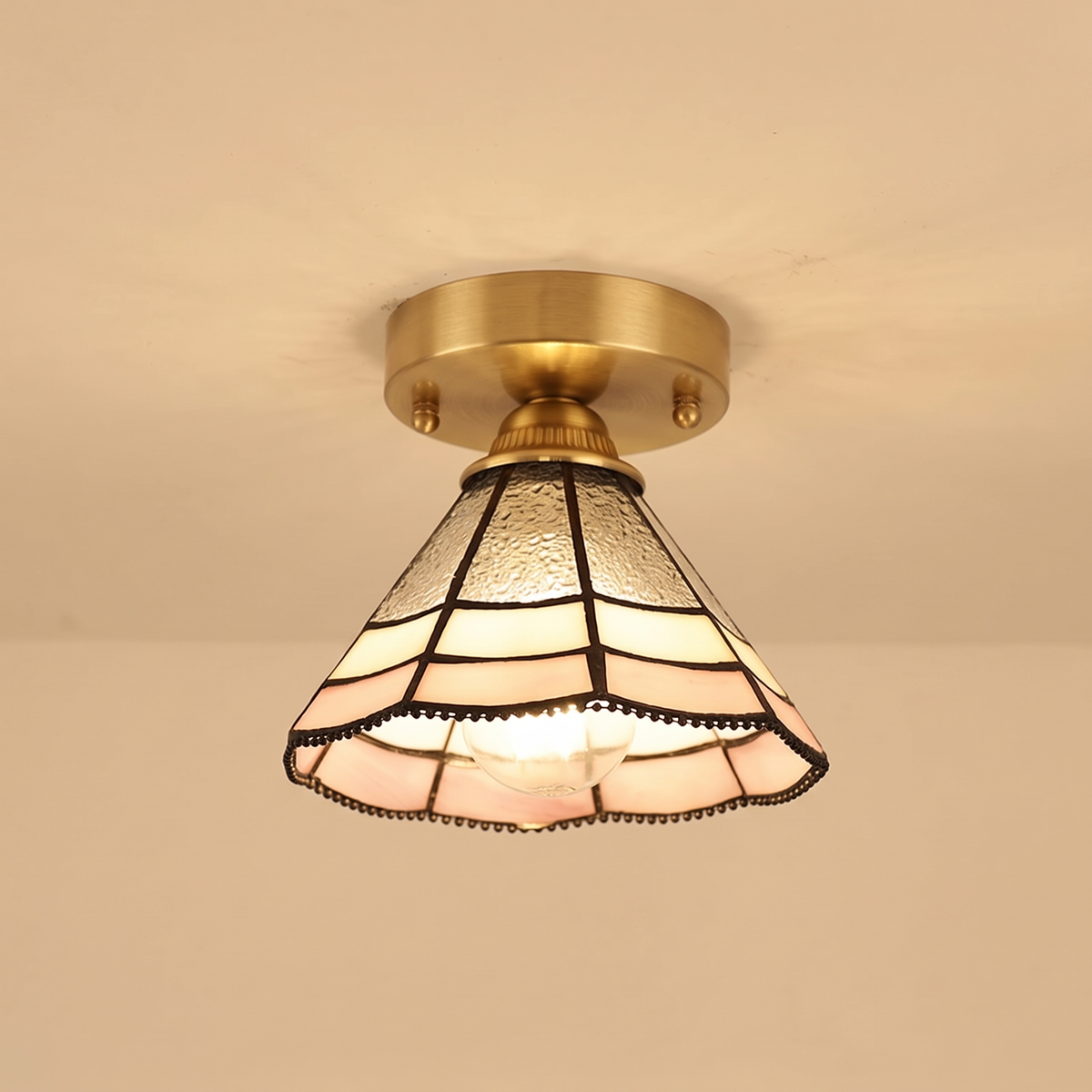 Orford stained glass flush ceiling light with clear, cream and blush leaded glass on a brass base, lit