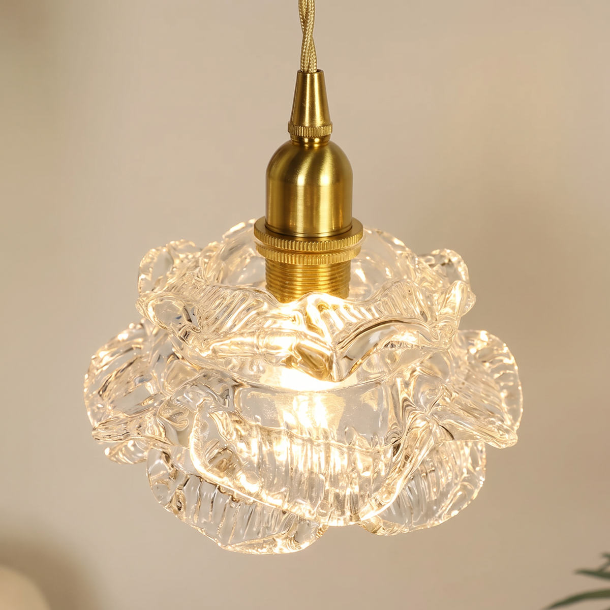 Close up of the clear Thorpeness ruffled rose glass petals and brass holder, lit