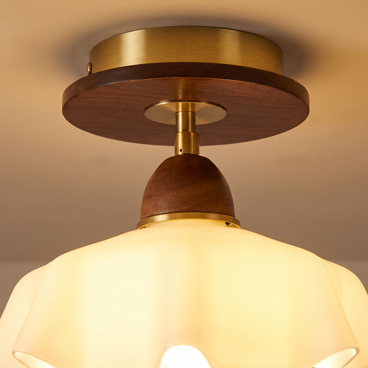 Close up of the Blakeney walnut toned wood, brass plate and frosted ruffled glass, lit