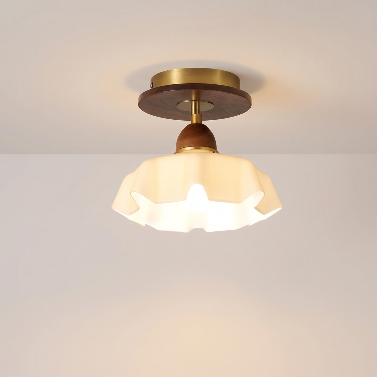 Blakeney semi flush ceiling light with a frosted ruffled glass shade, walnut toned wood and brass, lit