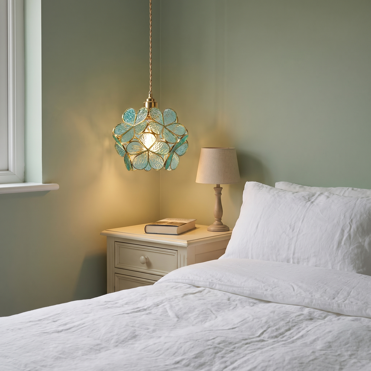 Halesworth glass petal pendant light hanging beside a bed in a sage green bedroom