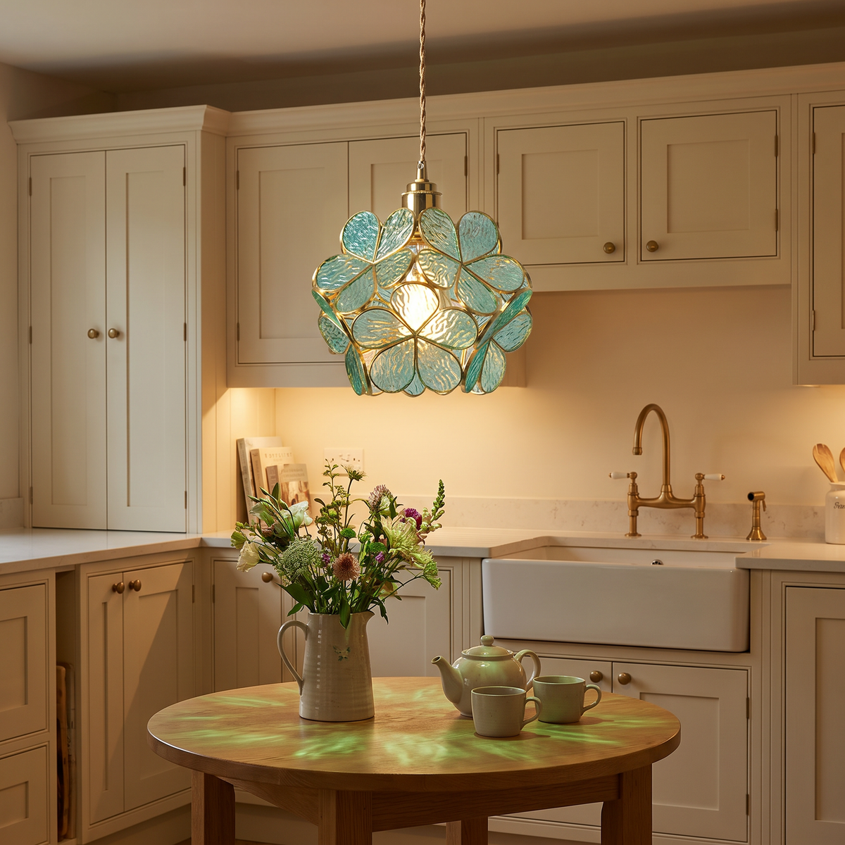 Halesworth glass petal pendant light glowing over a small oak kitchen table