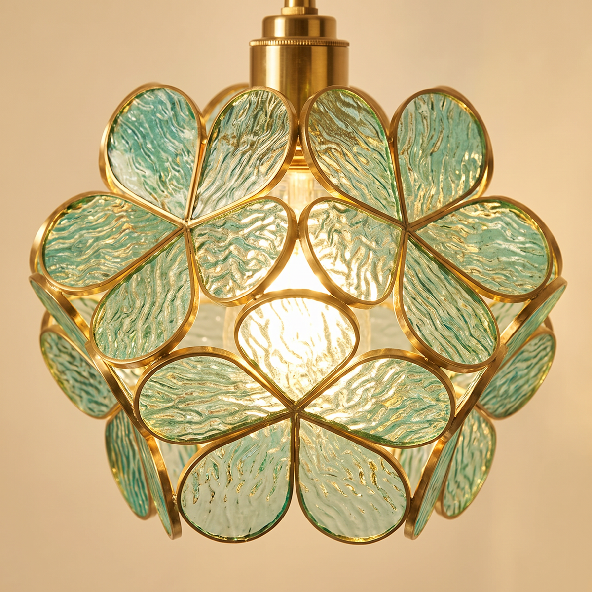 Close up of the Halesworth sea green textured glass petals and brass frames, lit