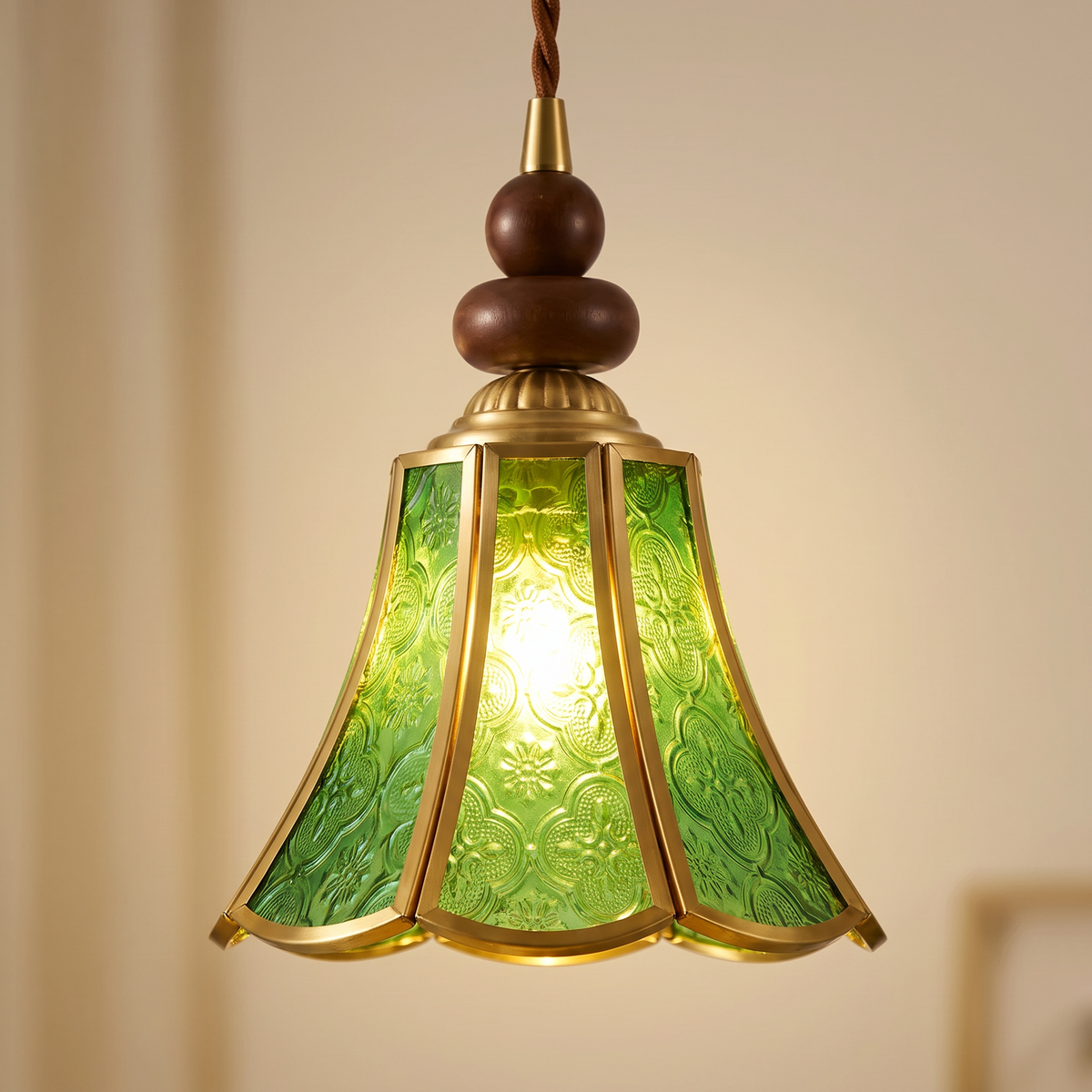 Close up of the Yoxford green embossed glass panels, brass tone ribs and walnut tone wood beads, lit