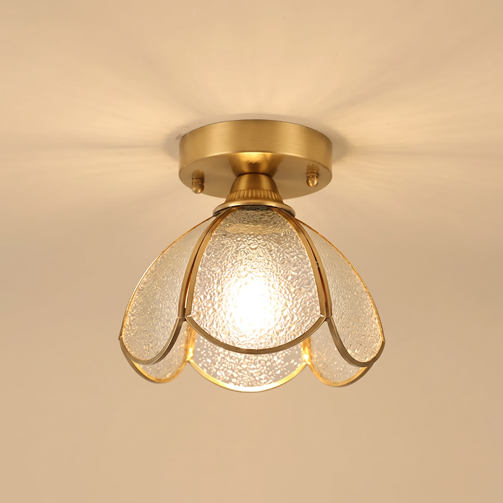 Hadleigh flush ceiling light with six petals of clear textured glass in a brass frame, lit