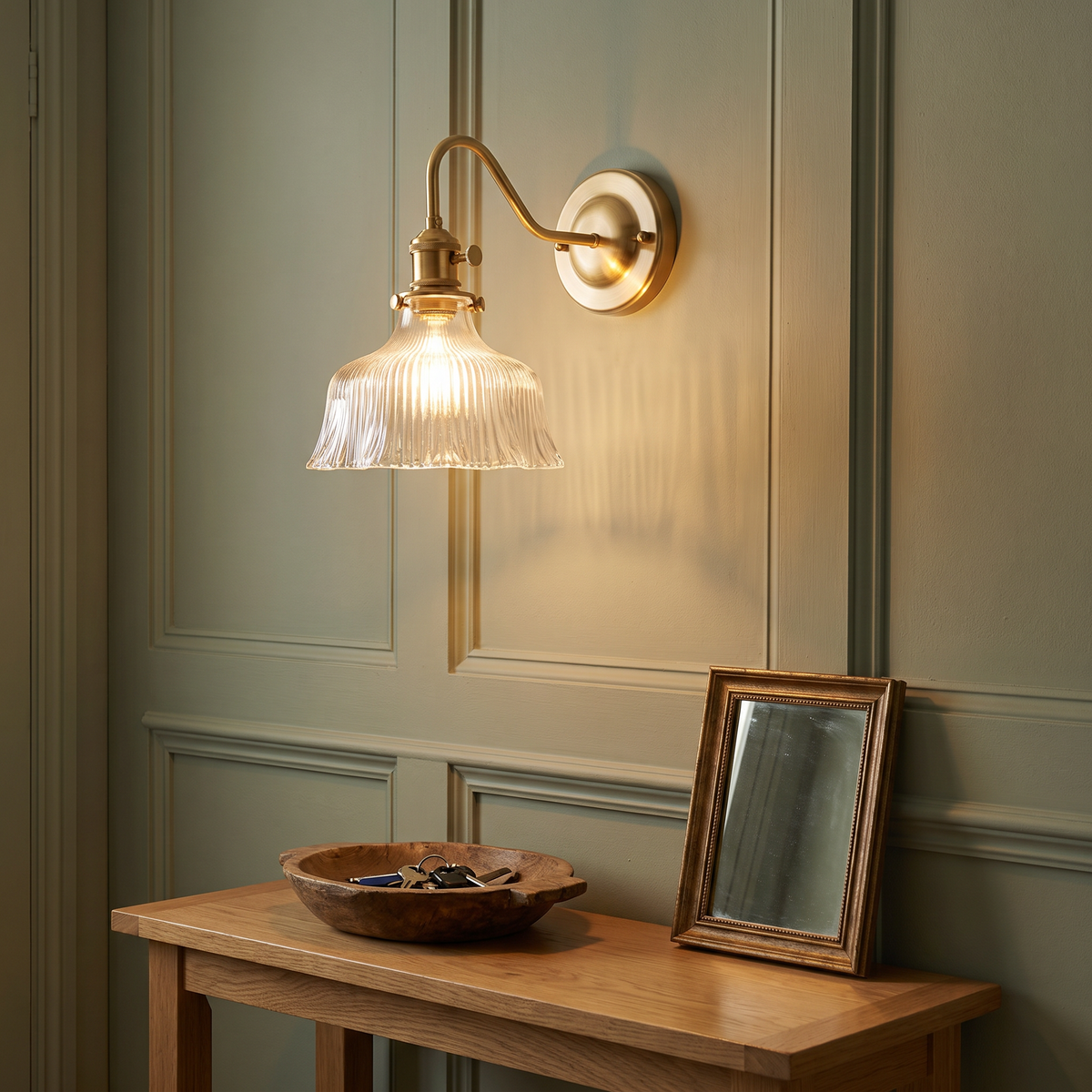 Clear Nayland fluted glass wall light glowing above a hall console table