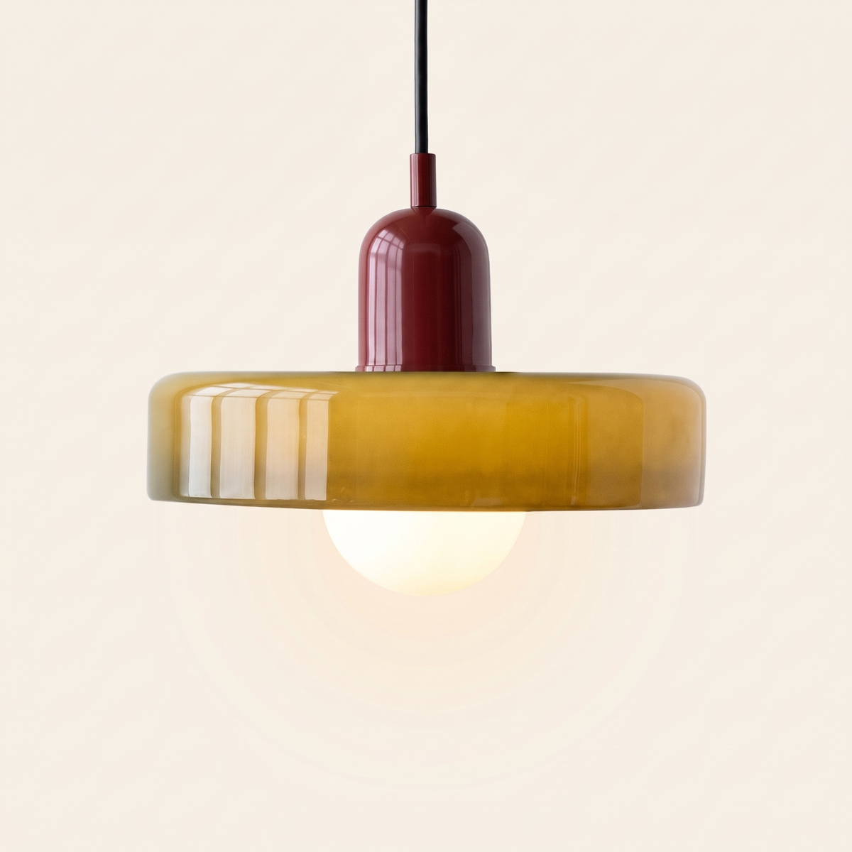 Welwyn mid century glass pendant light, olive glass disc with a burgundy cap, lit, on a cream background