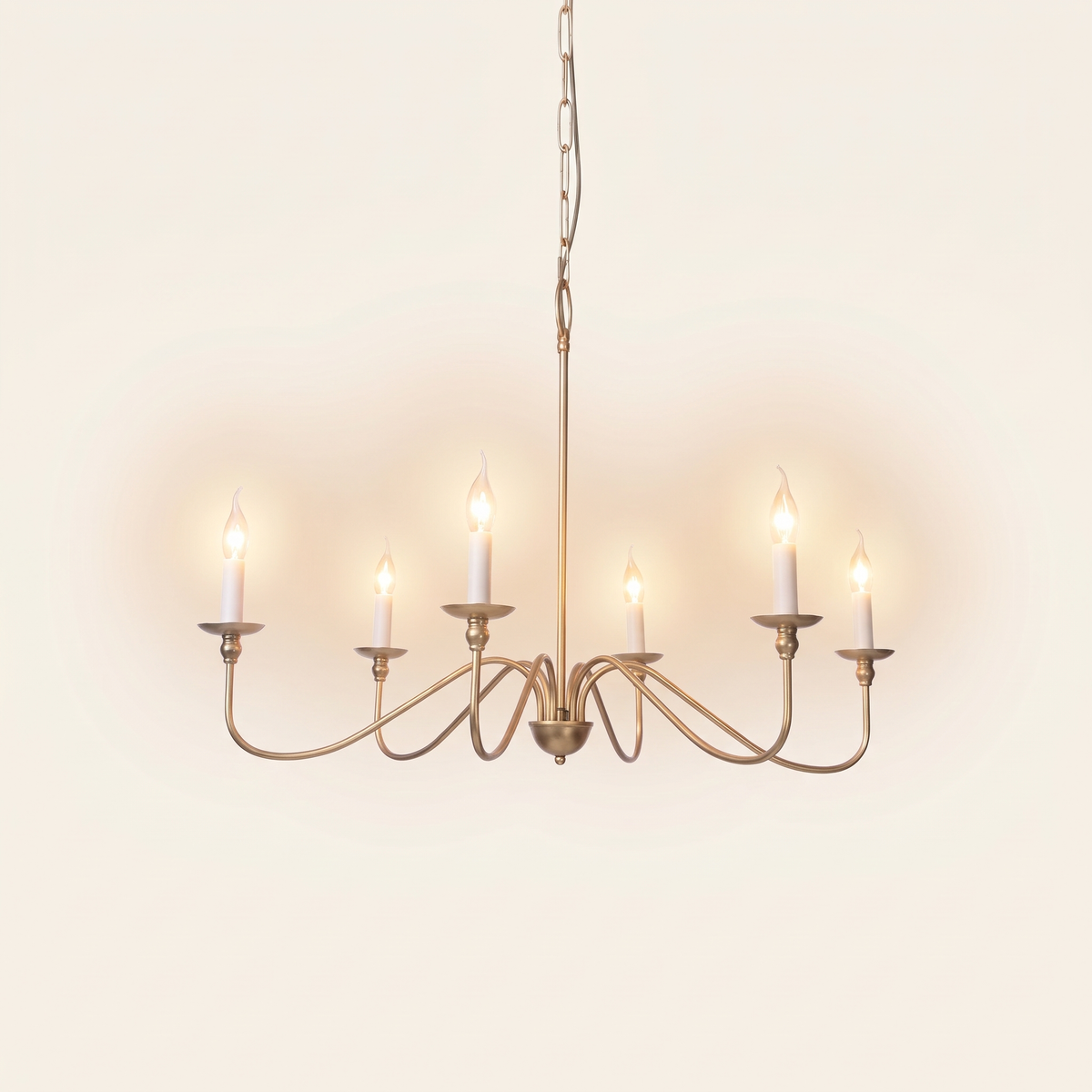 Ashworth gold six light candle chandelier, lit, on a cream background