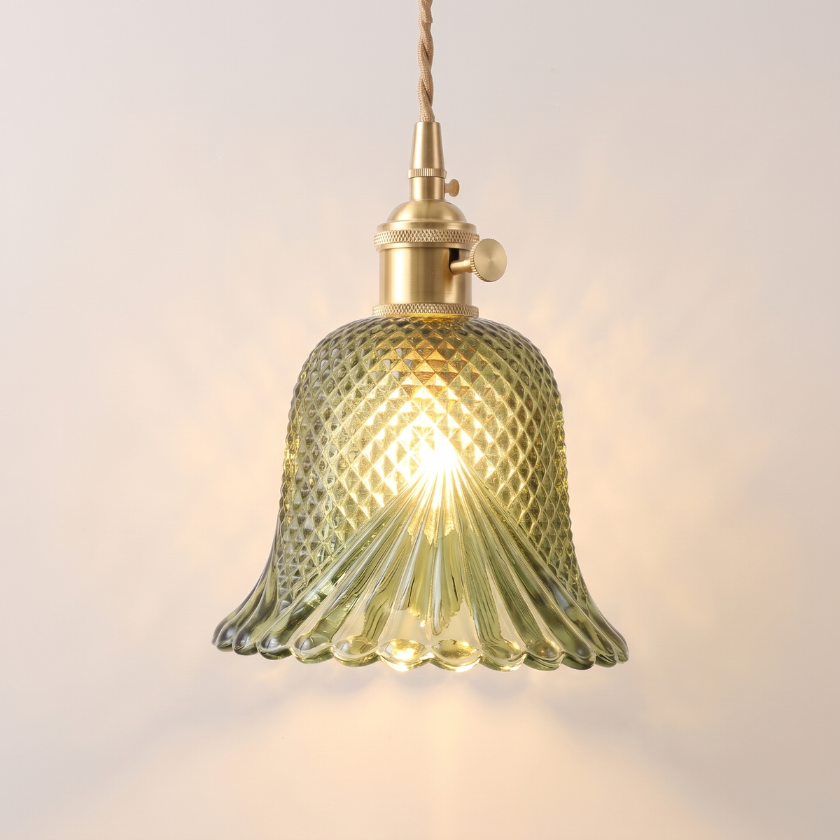 Lavenham cut glass bell pendant light in green glass with a brass lamp holder, lit