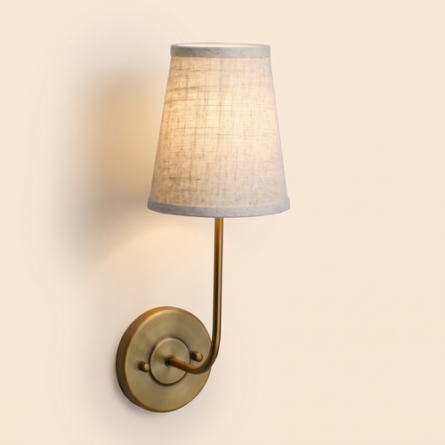 Hintlesham wall light in antique brass with a natural linen shade, lit, cream background