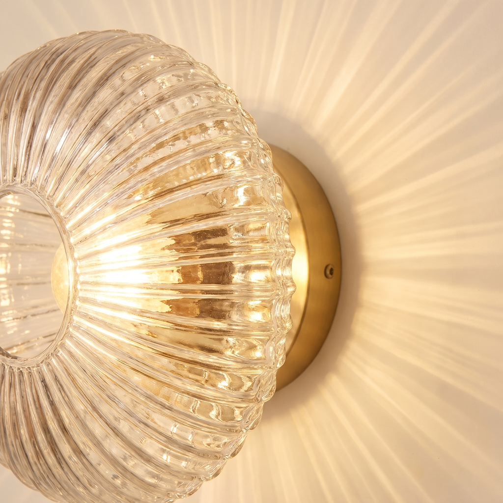 Close up of the ribbed clear glass of the Holton wall light, with rays of light across the wall