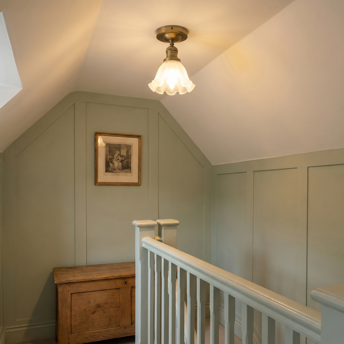 A lit antique brass Hoxne ceiling light on the sloping ceiling of a sage panelled cottage landing