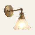 Hoxne wall light with a ruffled frosted glass tulip shade on a swivel arm and round wall plate in antique brass, cream background