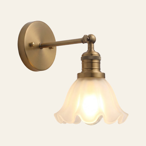 Hoxne wall light with a ruffled frosted glass tulip shade on a swivel arm and round wall plate in antique brass, cream background