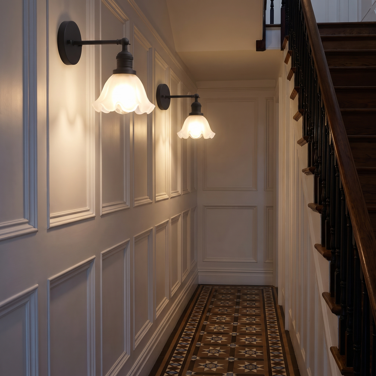 Two lit black Hoxne frosted glass wall lights along a white panelled hallway beside the stairs