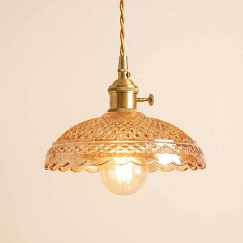 Huntingfield pendant light with a wide amber pressed glass dome and scalloped rim on a brass holder, cream background
