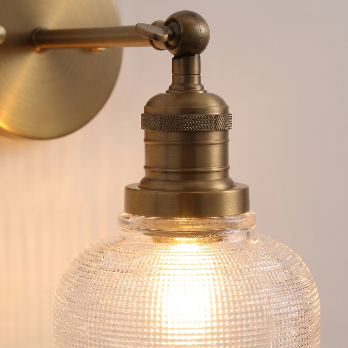 Close up of the Ixworth prismatic glass bell and the knurled antique brass lamp holder, lit