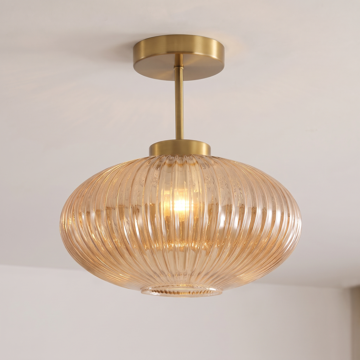 Close up of the Kelsale amber ribbed glass shade and brass stem, lit