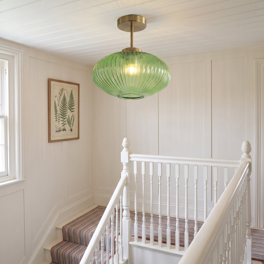 Green Kelsale ribbed glass ceiling light lit above a Victorian staircase landing with white banisters