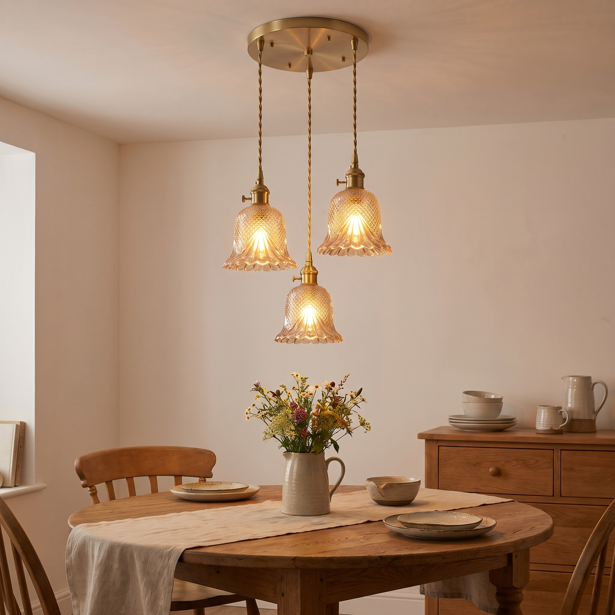 Amber Lavenham 3 light cluster glowing over a round oak dining table in a cottage dining room