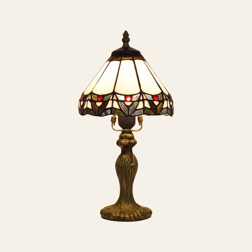 Melford stained glass table lamp, an ivory leaded glass shade with a scalloped border of red glass jewels on a dark bronze finish base, lit, cream background
