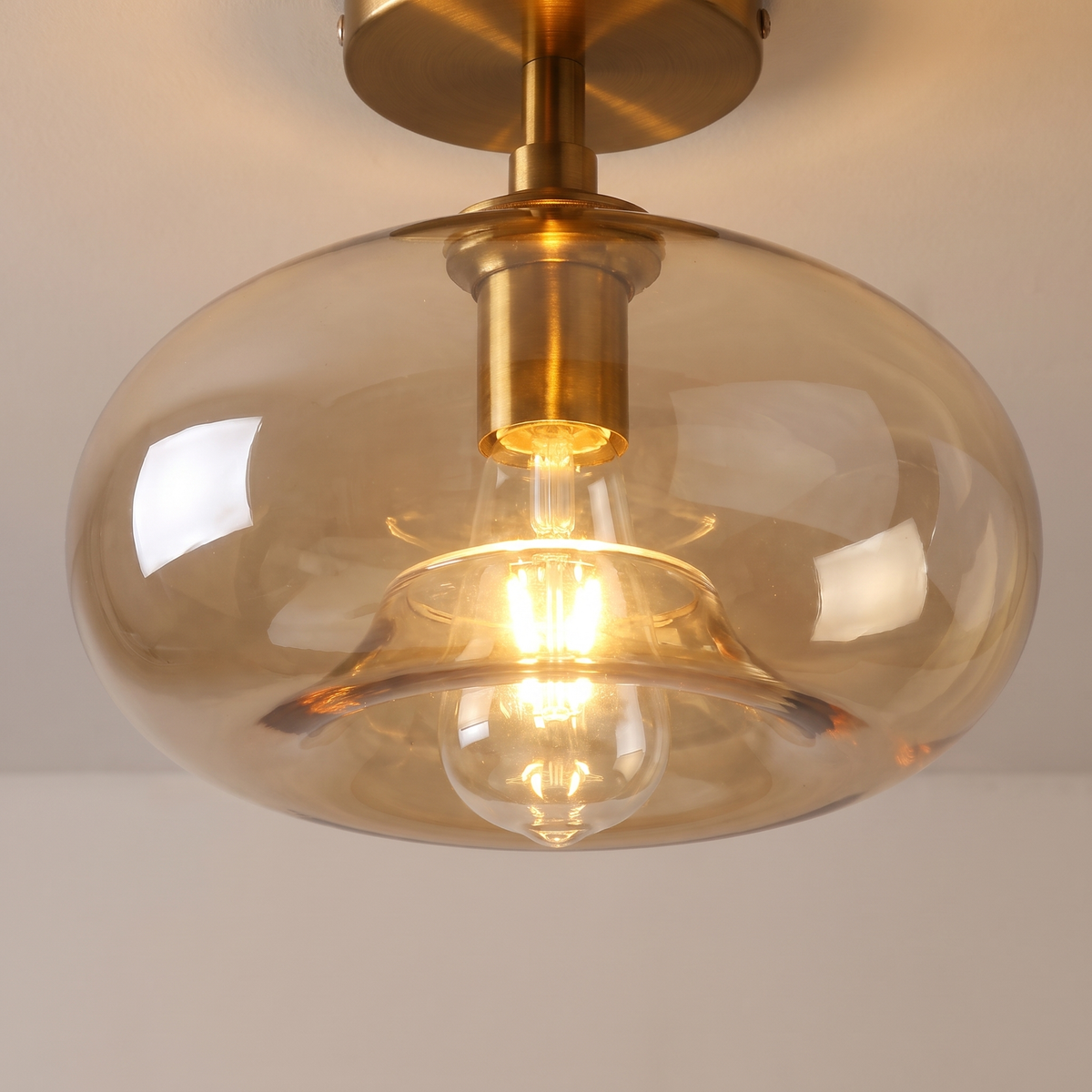 Close up of a lit Mendham shade showing the clear amber glass, the curved rim and the filament bulb inside