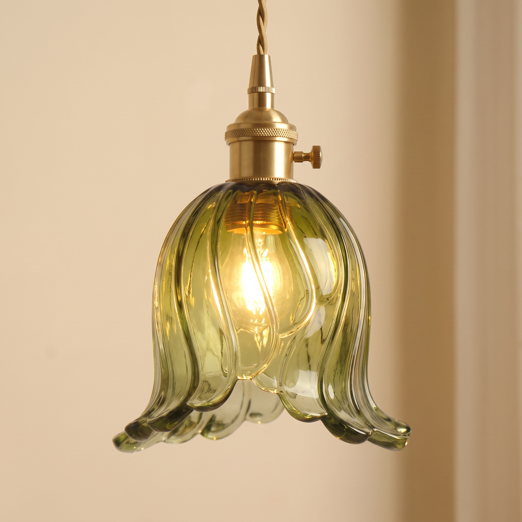 Close up of the green Metfield tulip shade with its petal hem and brass switch holder, lit