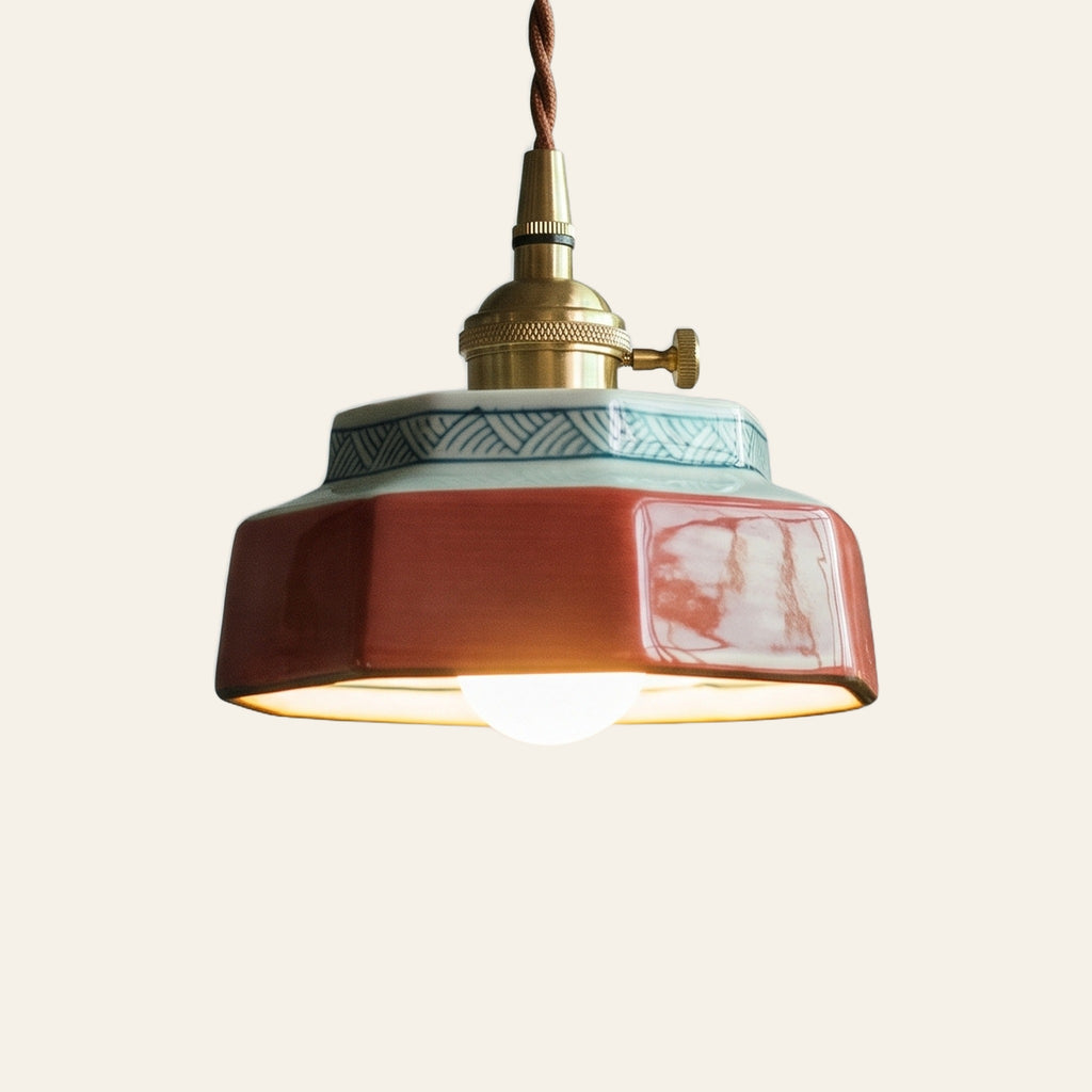 Mettingham pendant light, a small six sided coral red ceramic shade with a painted key pattern collar on a brass finish holder with a turn switch, lit, cream background