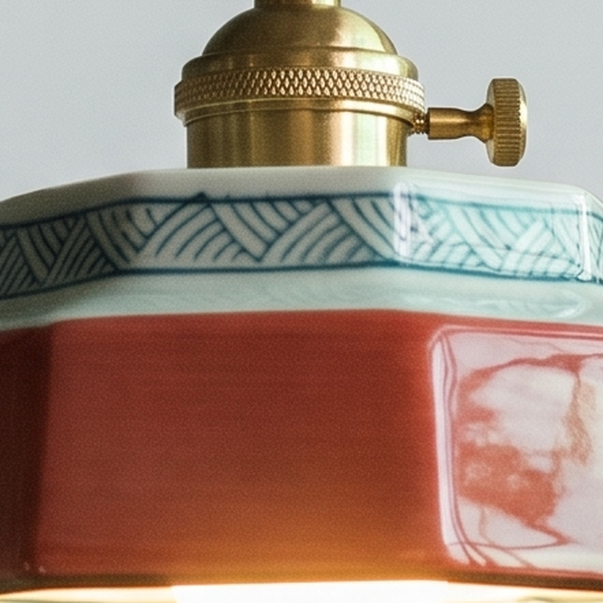 Close up of the painted key pattern collar, coral red glaze and brass holder with its turn switch on the Mettingham shade