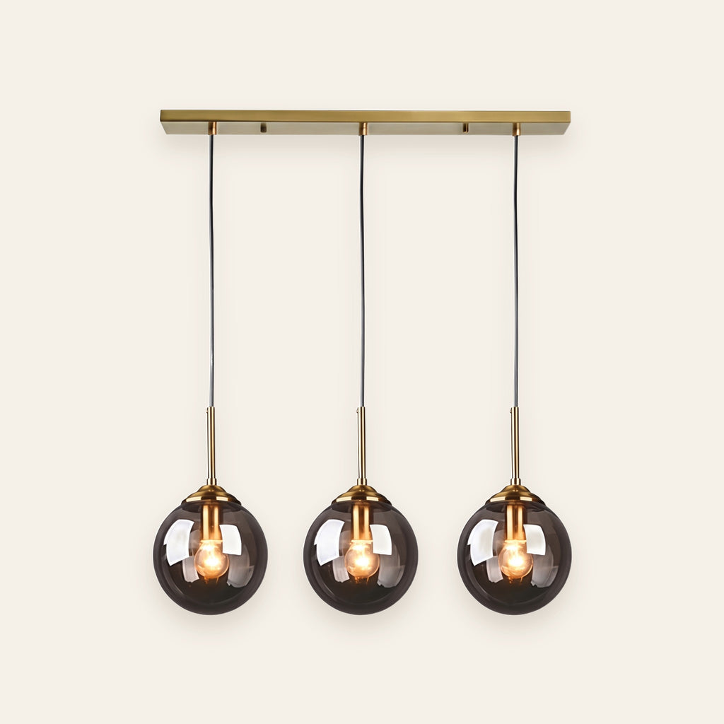 Orla three light smoked glass pendant on a brass bar, cream background