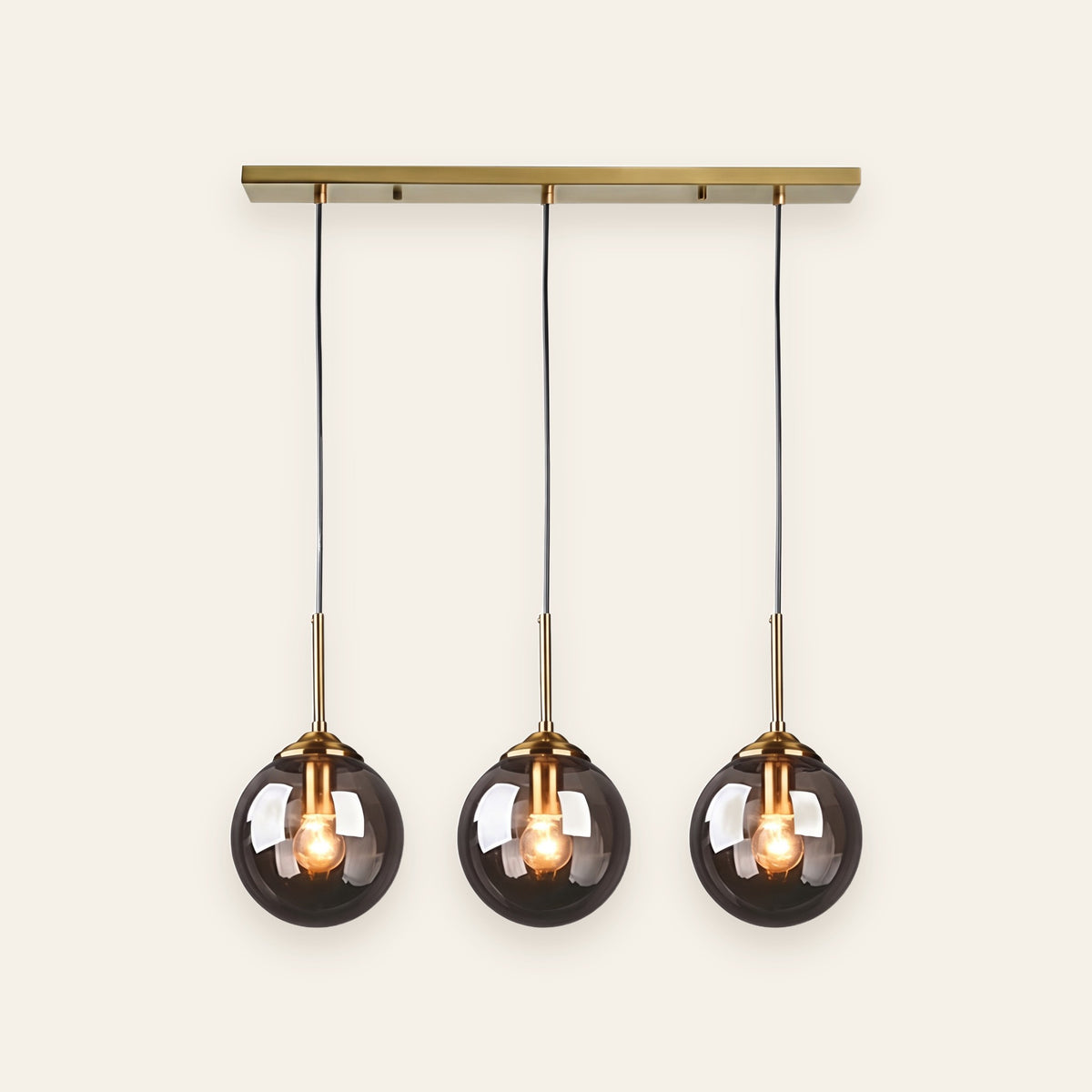 Orla three light smoked glass pendant on a brass bar, cream background