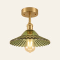 Peasenhall ceiling light with a green pleated glass cone shade on a brass rod and an exposed filament bulb, lit