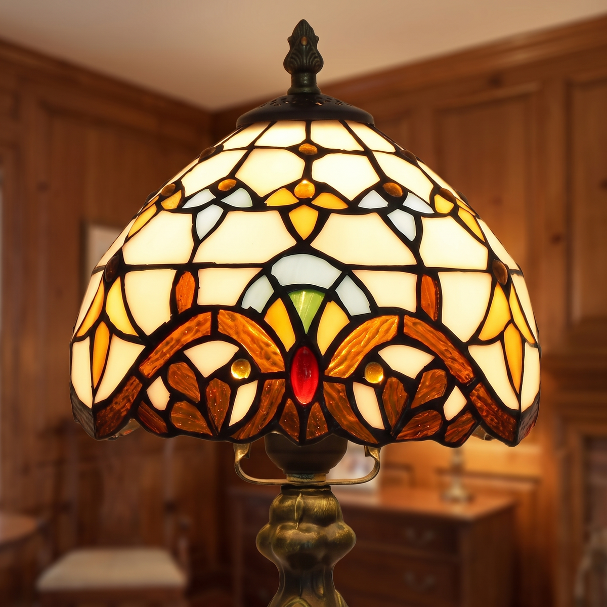 Close up of the lit Polstead shade: cream panels above amber and burgundy scrolls with red jewels
