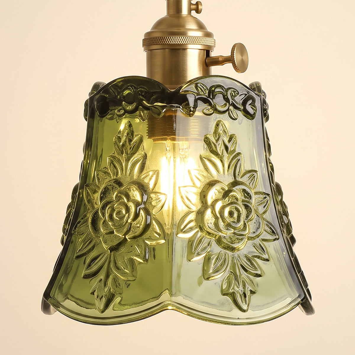Close up of the lit green Rendham shade: roses and leaves embossed in the glass with a ruffled rim