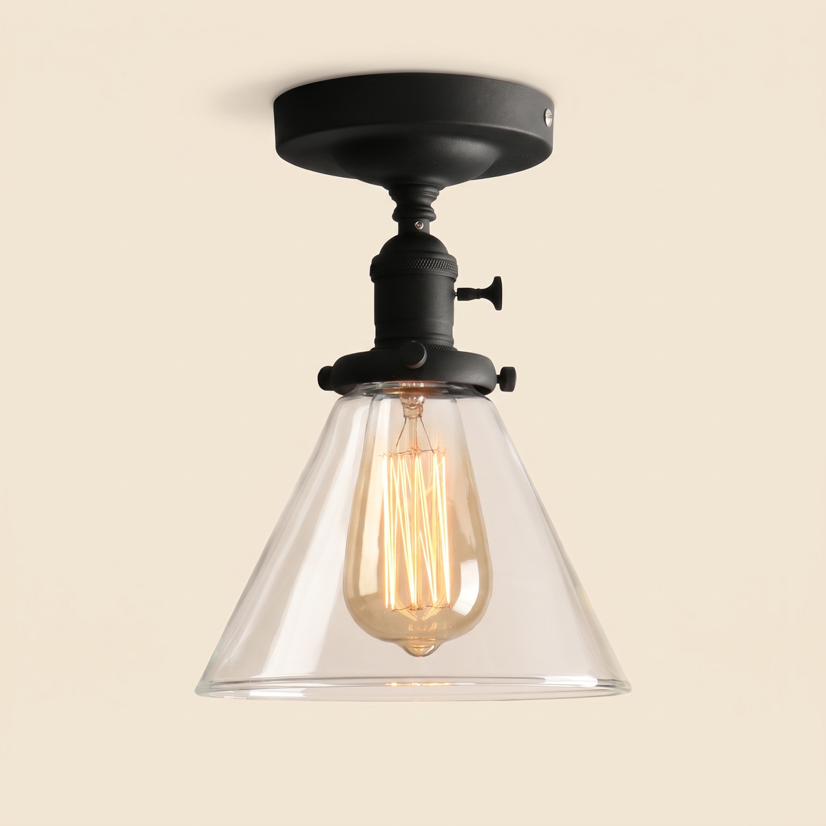 Shotley semi flush ceiling light in black with a clear glass cone shade, lit, cream background