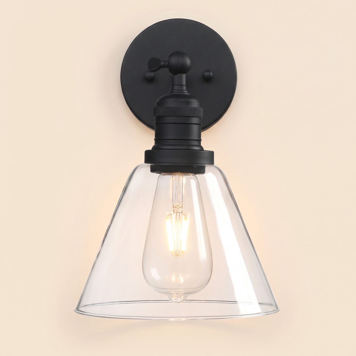 Shotley wall light in black with a clear glass cone shade, lit, cream background