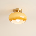 Stradbroke semi flush ceiling light with a rounded caramel glass mushroom shade on a brass finish ceiling plate, cream background