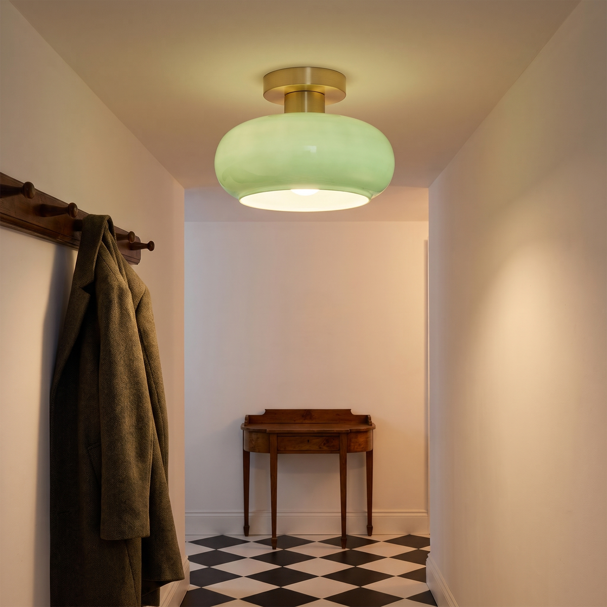 A lit sage green Stradbroke ceiling light in a white hallway with a coat rack and a chequered floor